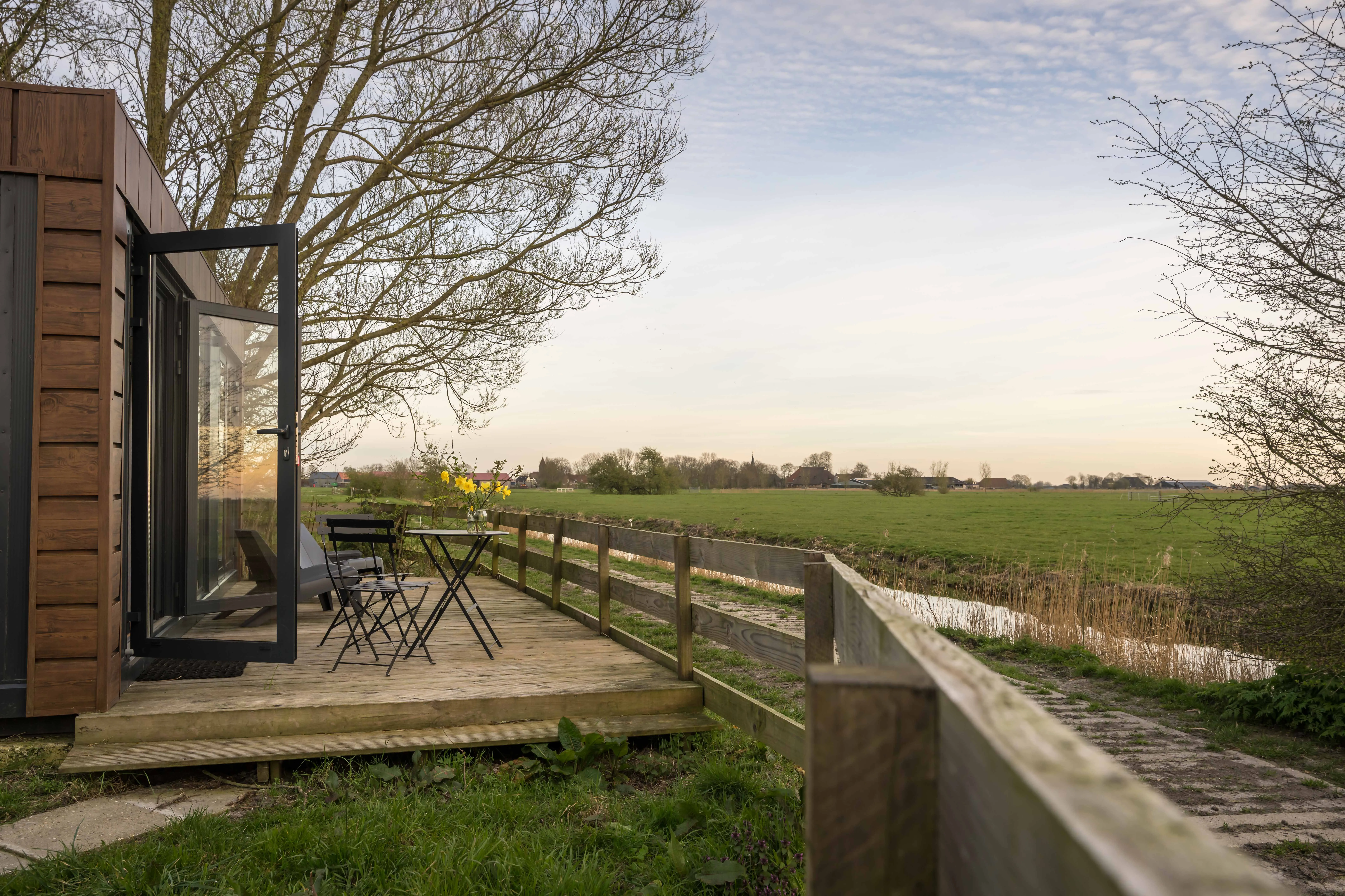 Het terras langs het natuurhuisje met uitzicht over de weilanden